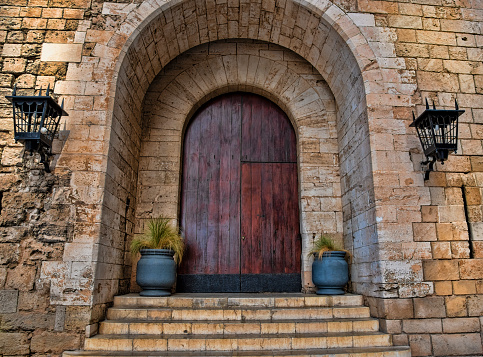 Exterior of Large old wooden door with brick and stone archway in Mallorca, Spain, with planters