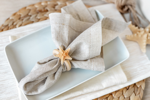 Sea inspired dining table place setting decoration with starfish and plates in pastel and neutral tones