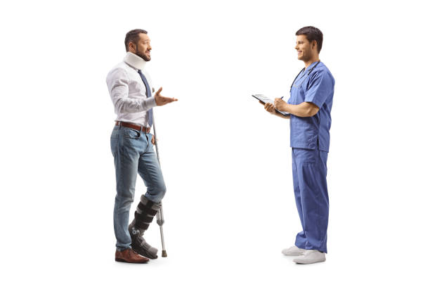 full length profile shot of an injured man with a walking brace and cervical collar talking to a healthcare worker - physical injury men orthopedic equipment isolated on white imagens e fotografias de stock