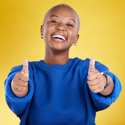 Laughing, portrait and black woman with thumbs up in studio isolated on a yellow background. Happy, emoji face and funny female with hand gesture for agreement, support or approval, like or success.