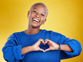 Heart hands, portrait and happy black woman in studio, background and color backdrop for emoji. Smile, female model and finger shape for love, thank you and support of peace, care or sign of kindness