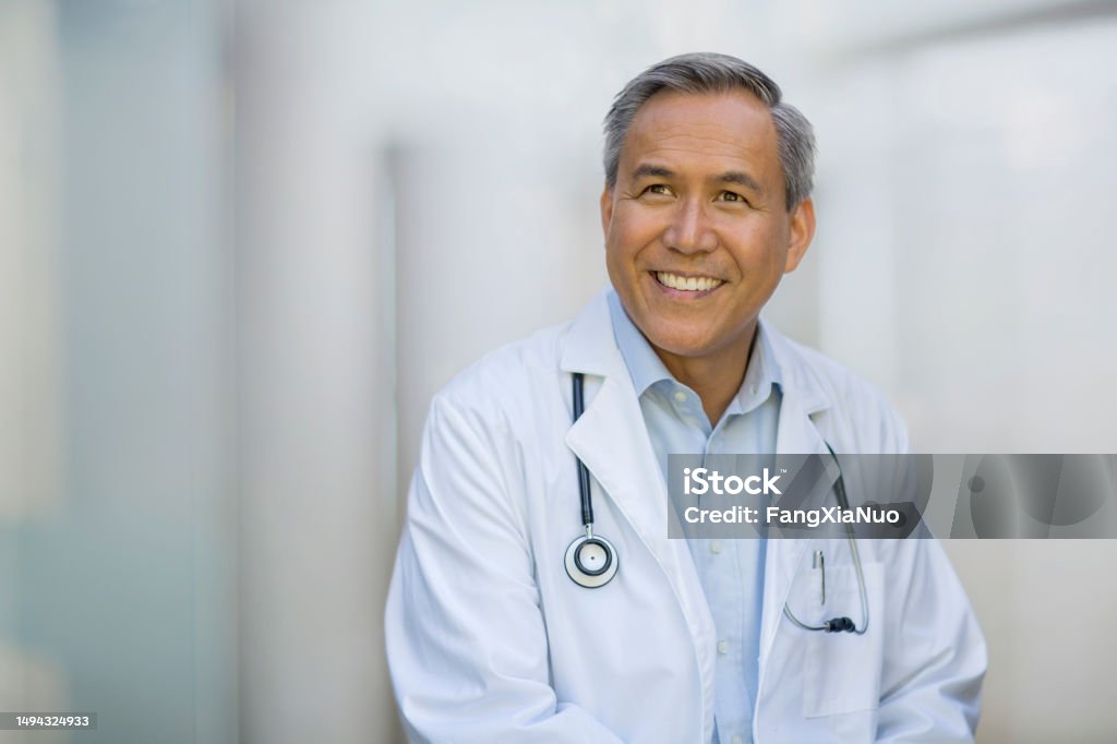 Portrait of Asian Chinese mixed race senior mature man doctor in collared business shirt smiling looking away Doctor Stock Photo