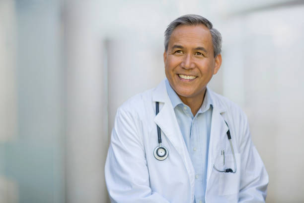 Portrait of Asian Chinese mixed race senior mature man doctor in collared business shirt smiling looking away stock photo