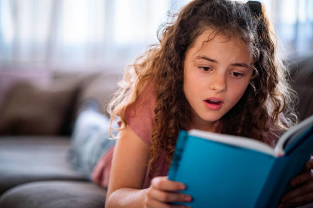 istock Schoolgirl reading a book at home 1494325348