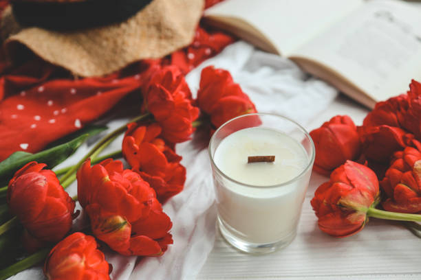 istock Candle, tulips and open book in home interior. 1494325619