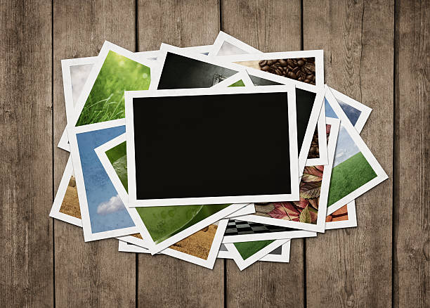Stack of old photographs at grunge wooden background with clipping path for the blank one