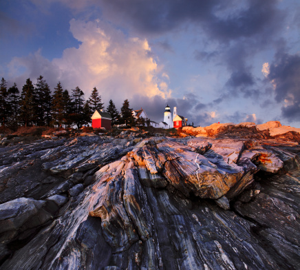 A Stormy Sunset Casts Dramatic Light Over The Rugged Sea Coast At The Foot Of The Pemaquid Point Lighthouse, Bristol Maine, USA