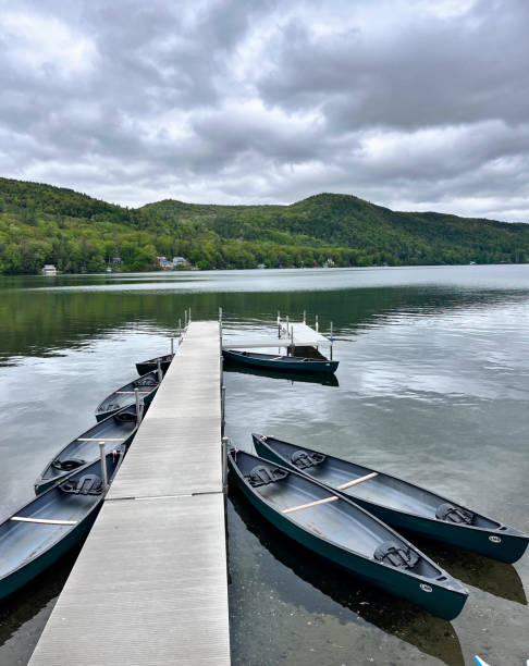 istock long pier with boats on lake (dock for canoes and kayaks with mountain view and dark cloudy sky) reflection, rowing 1494330982