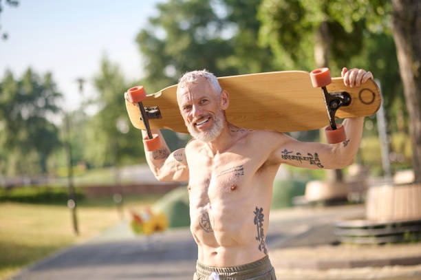 istock Smiling mature man holding longboard in a city park. 1494335547