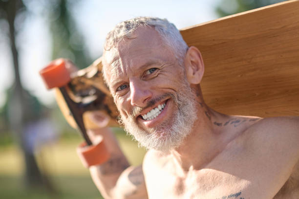 istock Smiling mature man holding longboard in a city park. 1494335549