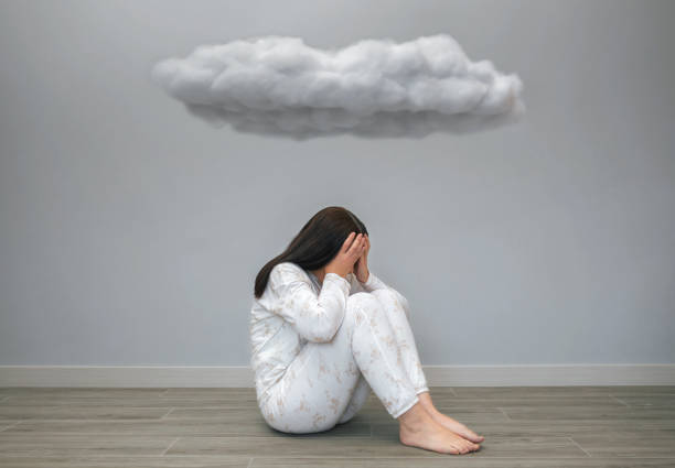 istock Woman with mental health problems covering her face with hands under a dark cloud 1494335698