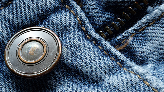 Focus-stacked macro photo of denim blue jeans with brass button and zipper detail.