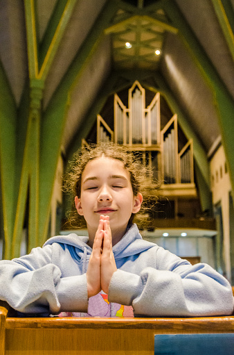 Teenage girl praying in  Notre Dame Sanctuary of Trois-Rivières. 
The pipe organ is in background