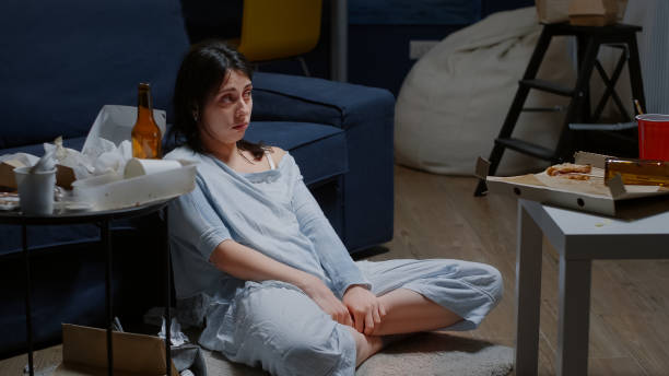 istock Depressed young woman sitting alone on floor crying looking at camera 1494343483