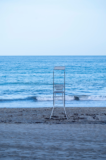 A metallic tower or chair or lifeguard post in the sand of the beach in the Mediterranean sea.