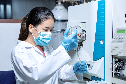 Scientist woman using a micropipette for sample preparation with the vial for Liquid Chromatography mass spectrometry LC-MS analysis in the laboratory. The LC-MS was used for pharmacology, chemistry, and biotechnology.