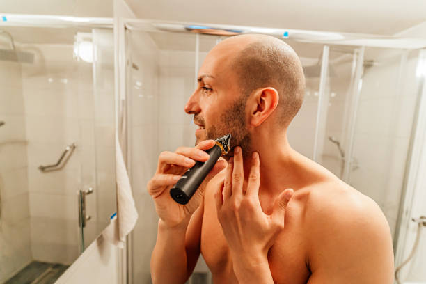 istock Young man trimming his beard with a trimmer 1494345455