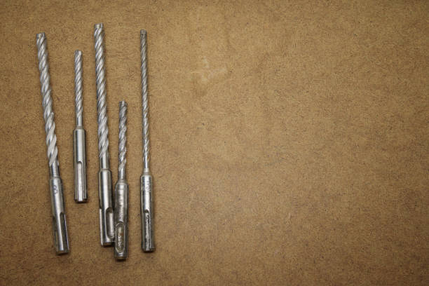Selection of masonry drill bits on top of the brown MDF board