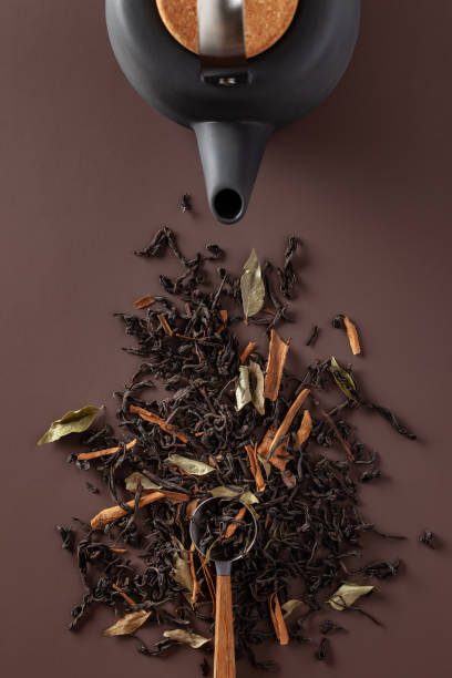 Tea leaves and teapot on a brown background stock photo