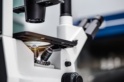 Closeup of the inverted microscope, microscopy with metal lens for bioassay in the laboratory. Research for pharmaceutical, medicine, and biotechnology development in the lab.