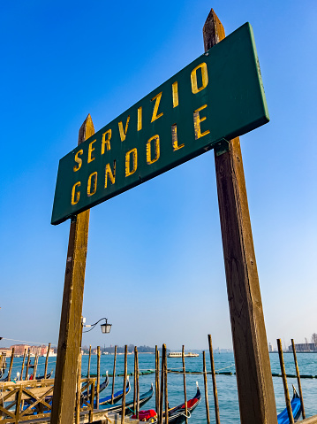 Green direction sign in Italian language Servizio Gondola = Gondola Service offering at the Grand Canal in Venice, in Italy. Travel destination background with copy space.