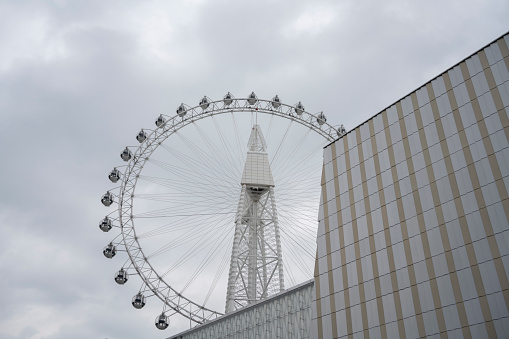 Looking up at part of a large Ferris wheel with dark clouds.