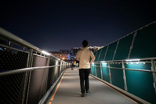 man running on bridge at night