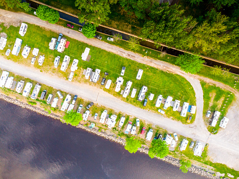 Aerial view of motorhomes in a grass parking lot besides the St. Lawrence river in the summer morning in Trois-Rivieres