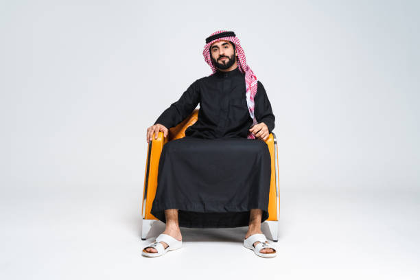 Handsome arab middle-eastern man with traditional saudi clothing in studio - Arabic muslim adult male businessman wearing thwab portrait isolated on gray background