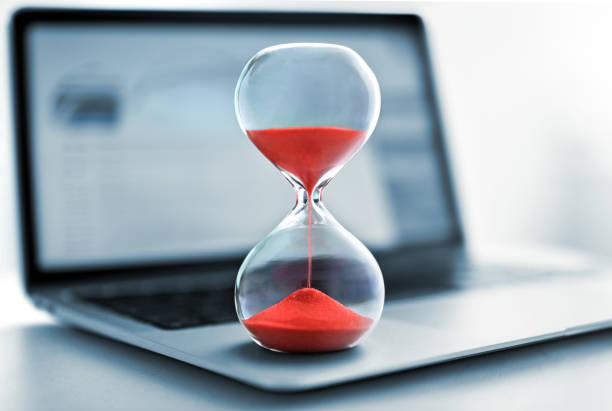istock Hourglass with red sand stands on the laptop computer 1494362790