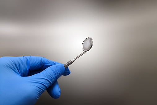 Closeup Image Of Dentist Holding Dental Mirror With Gloved Hand