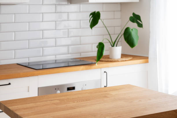 istock Wooden tabletop with free space for product montage or mockup against blurred white kitchen with cutting board and plant in scandinavian style 1494364807