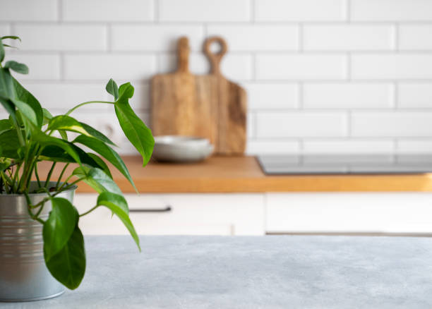 istock Wooden blue table top with flower pot against blurred white kitchen with cutting board in scandinavian style 1494364898