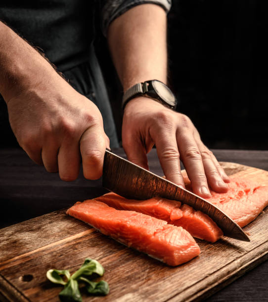 istock chief cutting a salmon fillet into pieces for cooking 1494365878