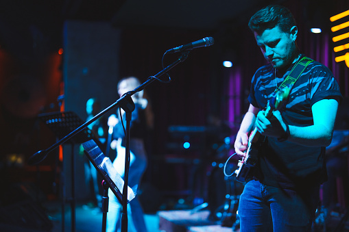 The bass guitarist plays the bass guitar. Dark key. Selective focus