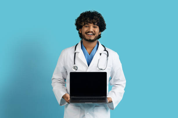 istock Cheerful hindu doc holding laptop with empty screen, mockup 1494372067