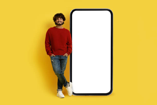 istock Positive young indian man standing by huge smartphone, mockup 1494372072