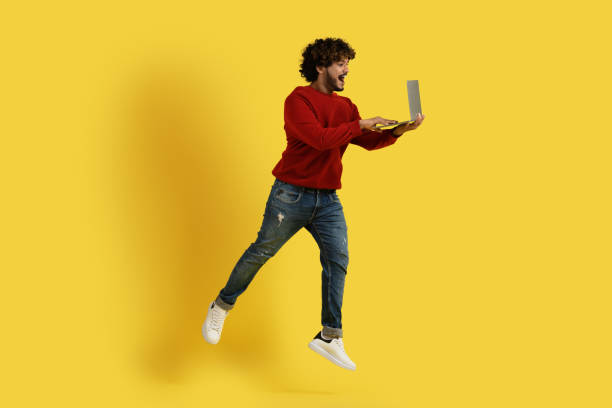 istock Excited hindu guy using laptop and jumping up 1494372073