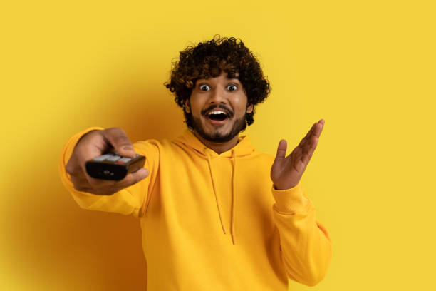 istock Happy emotional young indian man holding TV remote control 1494372089