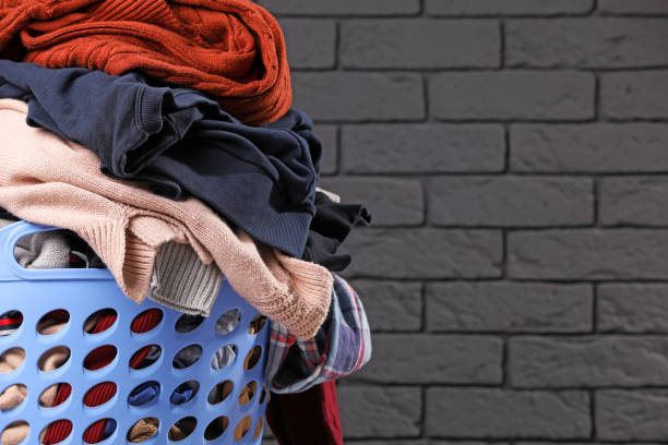 istock Laundry basket with clothes near black brick wall. Space for text 1494372381