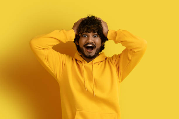 istock Emotional young indian man touching his head on yellow 1494372684