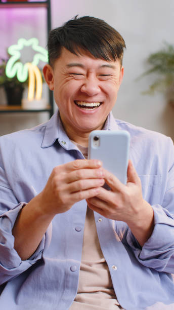 istock Happy asian man at home use smartphone typing browsing wow yes found out great big win celebrate 1494373402