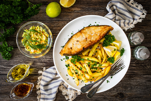 Fried halibut and French fries on wooden table