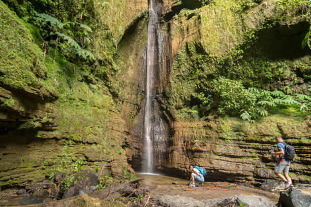 Two people at Ribeira Quente waterfall, Azores Two people at Ribeira Quente Waterfall on São Miguel, the Azores madalena stock pictures, royalty-free photos & images