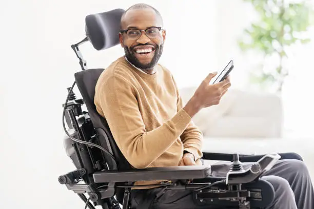 Photo of Disabled Black Man Using Smartphone at Home