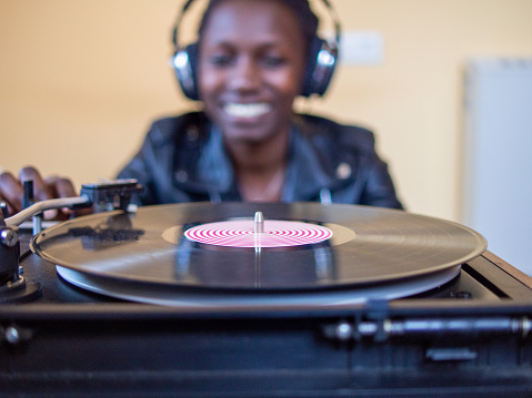 African woman wearing headphones while having a vinyl dj session with a turntable