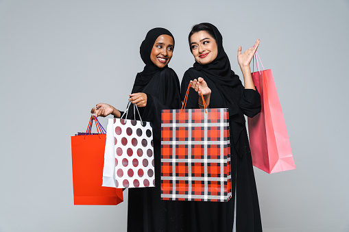 Beautiful arab middle-eastern women with traditional abaya dress and shopping bags in studio - Arabic muslim adult female portrait in Dubai, United Arab Emirates