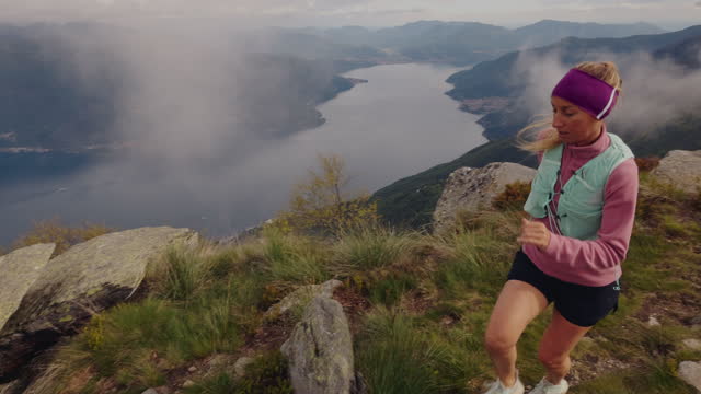 Slow motion: Female trail runner crosses mountain ridge