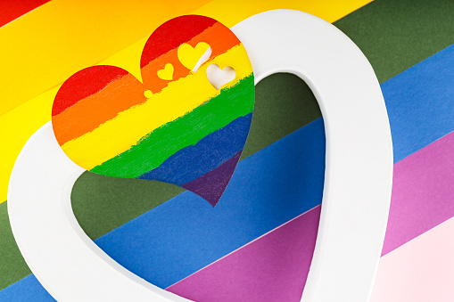 Rainbow heart and white heart on LGBT Pride flag. LGBT equal rights movement and gender equality concept. Close up