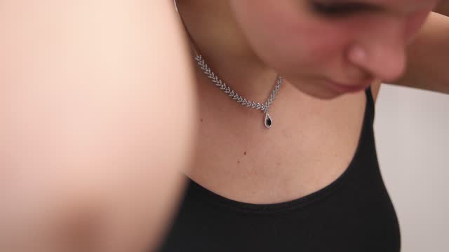 Young woman put on a silver necklace with black gemstone